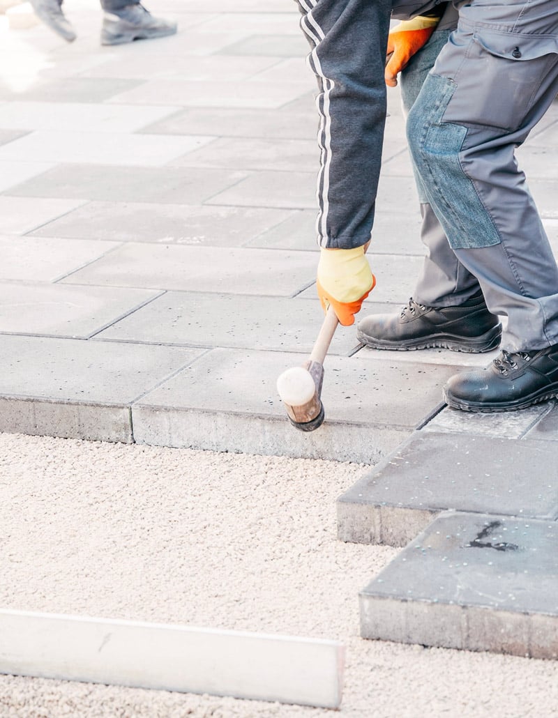 construction worker replacing sidewalk bricks