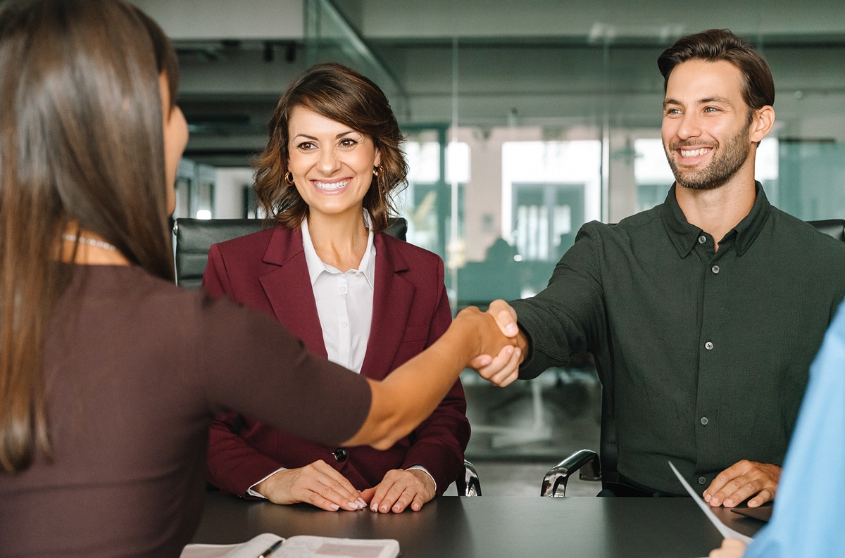 couple shaking hands with board member