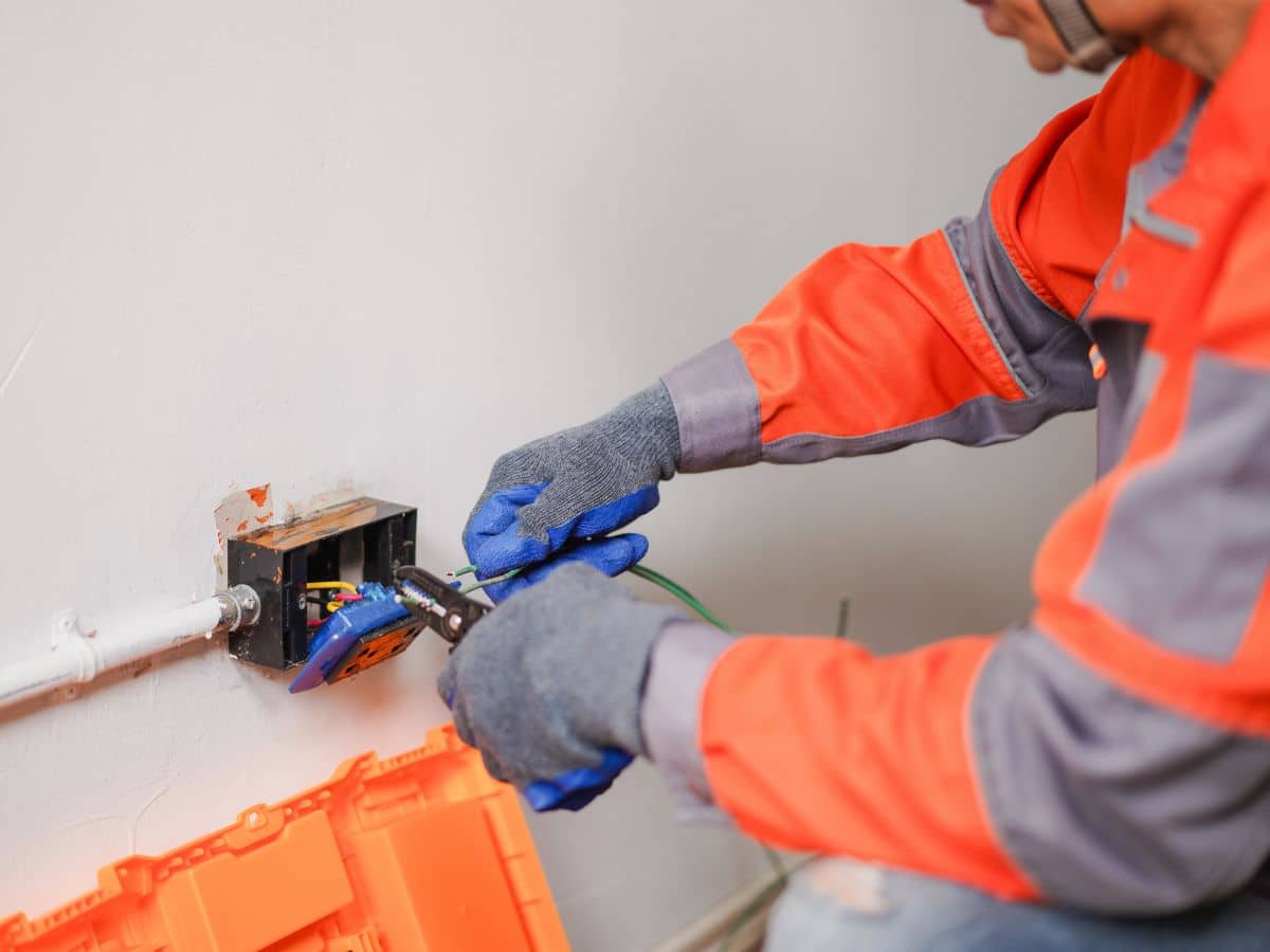 electrical maintenance worker checking housed switch wall