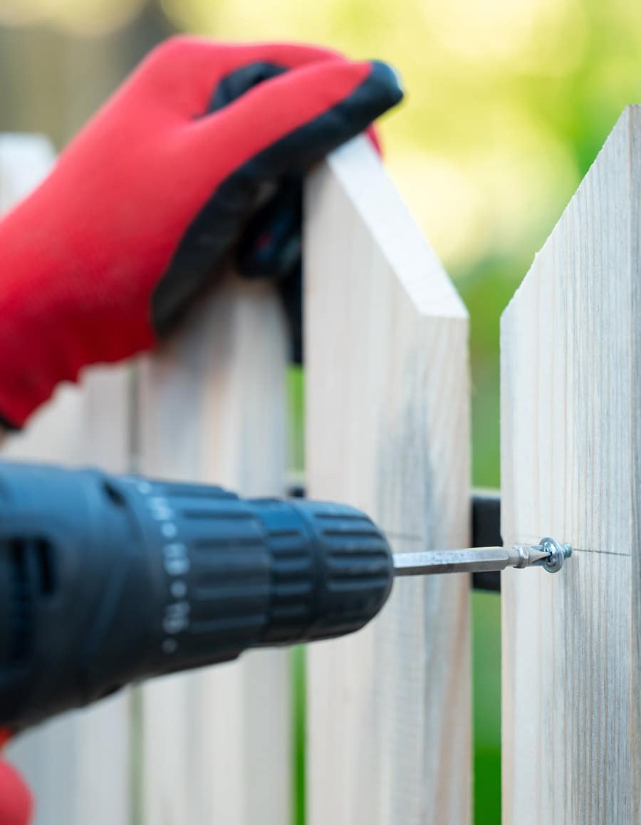 fence repair man fixing picket fence