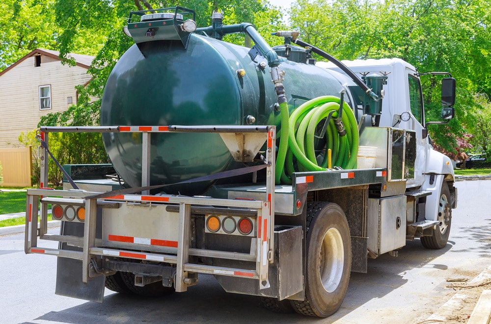 green vacuum truck in residential neighborhood