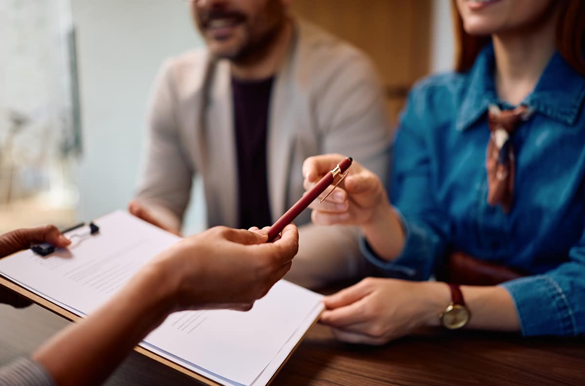 insurance agent handing pen to client