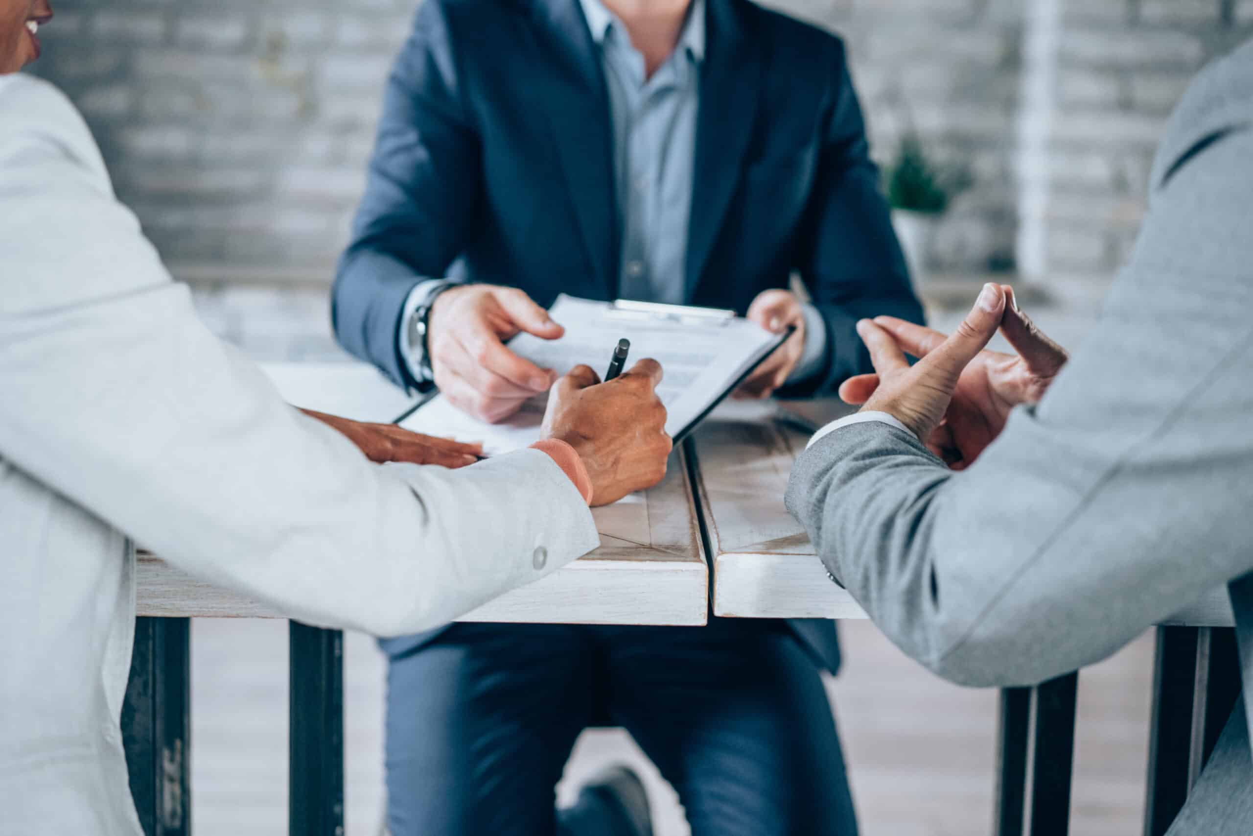 Two clients signing paperwork with a business representative