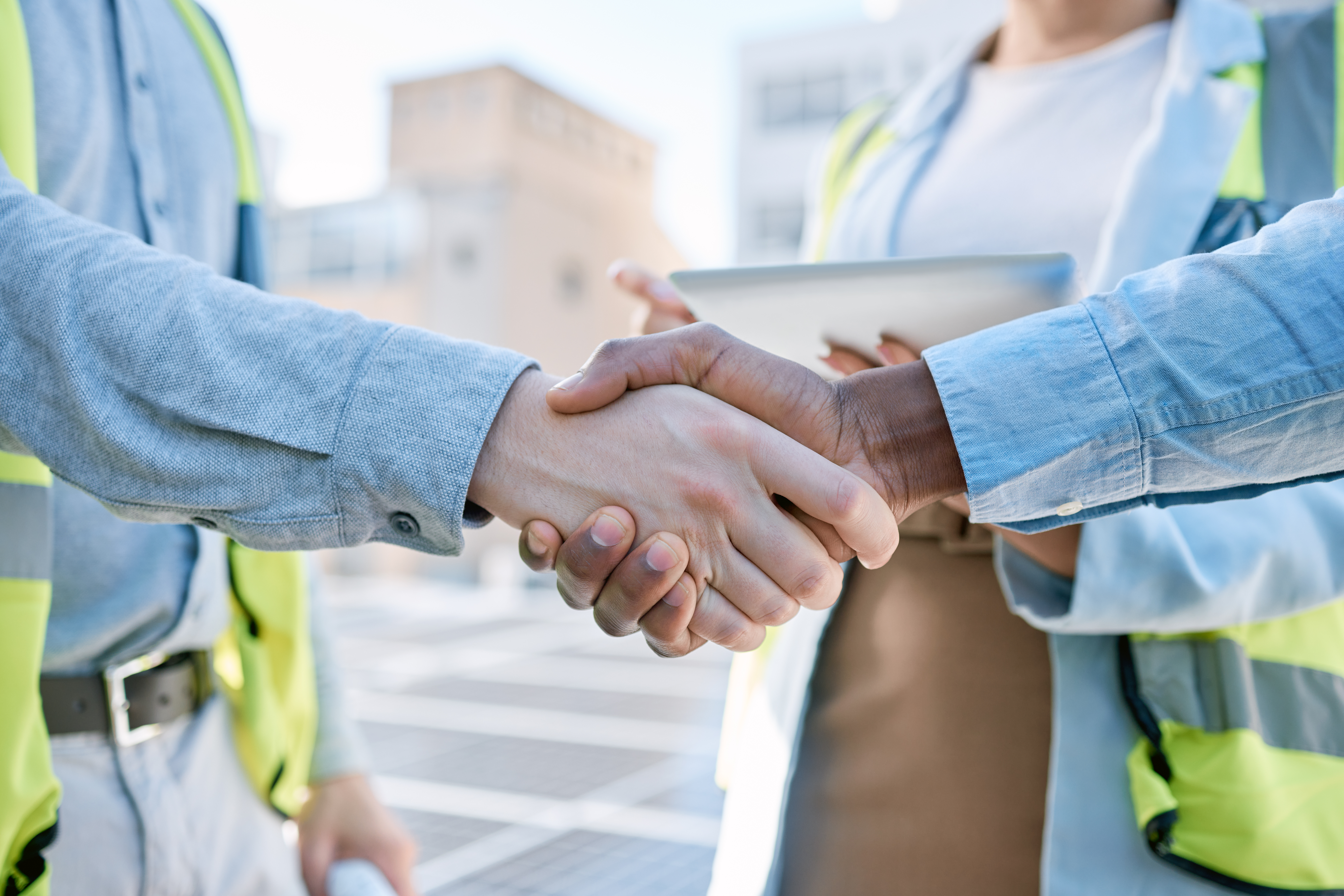 Two professionals shaking hands at a solar panel site, symbolizing a sustainability agreement