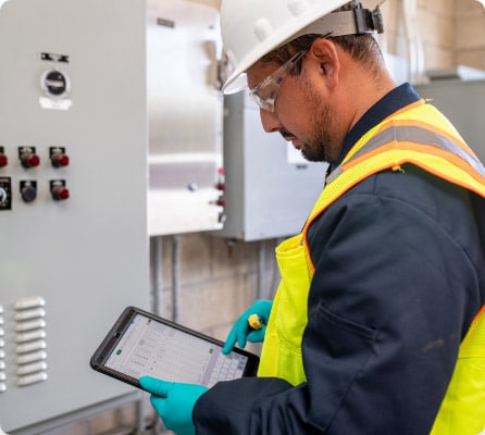 man in safety vest and hardhat checking his ipad