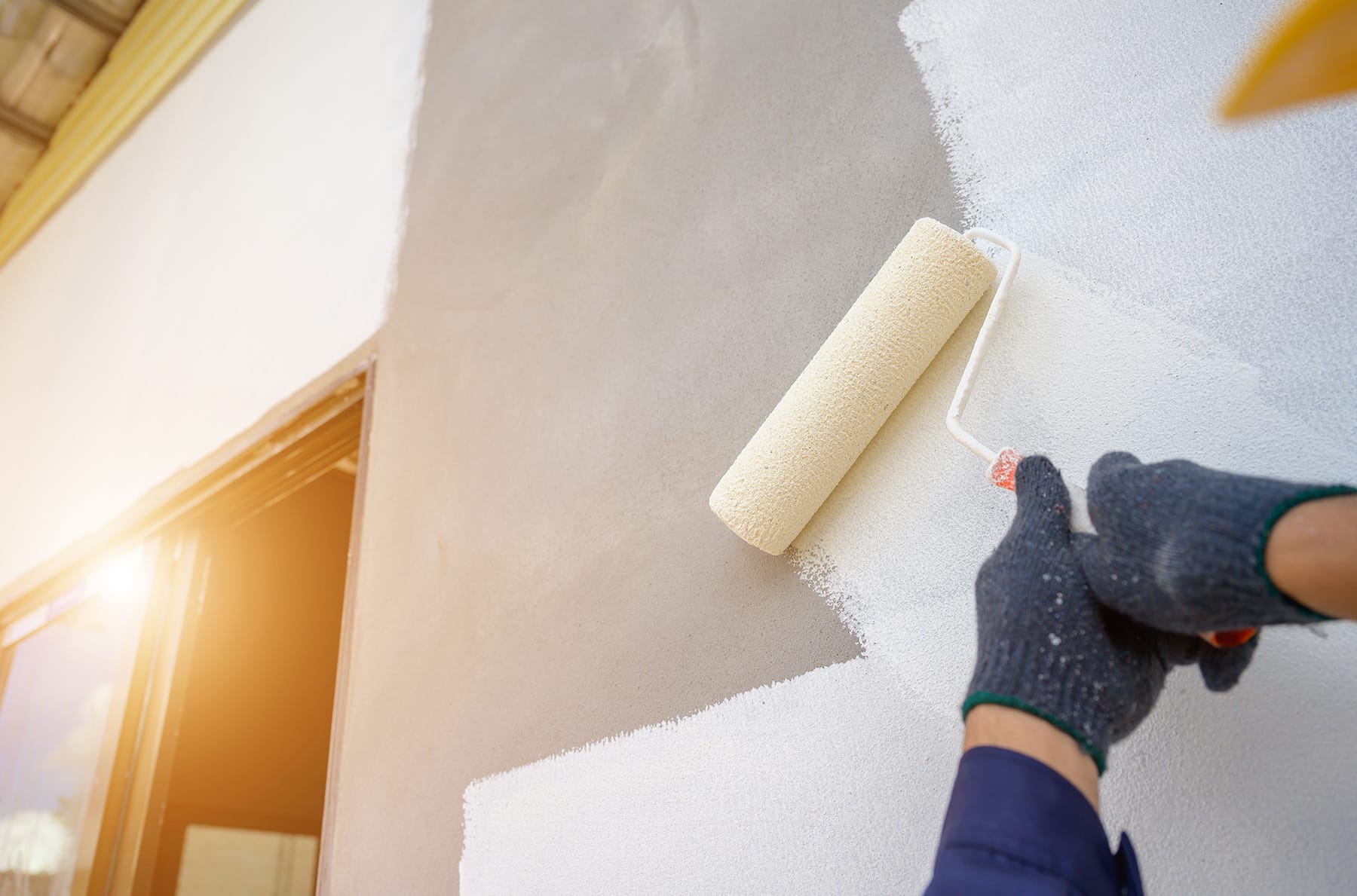 maintenance painter using roller on house wall