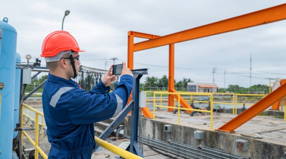 Technician photographing plant equipment on a smartphone to document an inspection