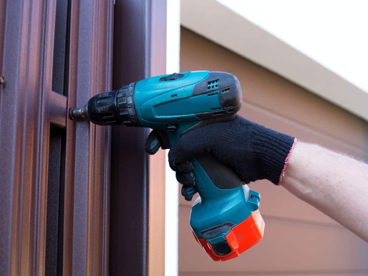 maintenance worker blue drill wooden fence