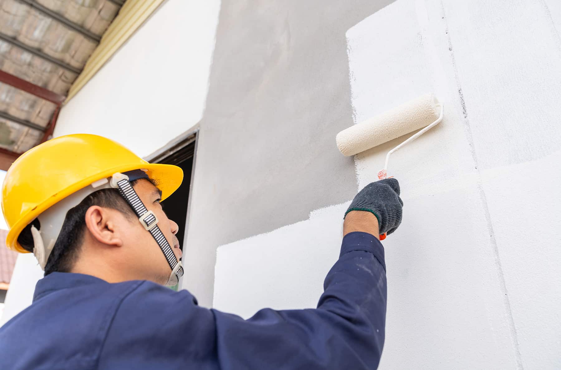 maintenance worker painting exterior house