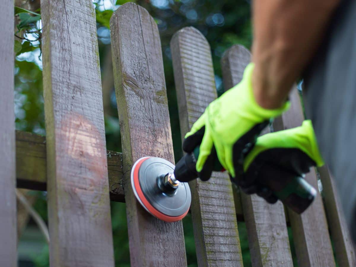maintenance worker sanding wooden fence