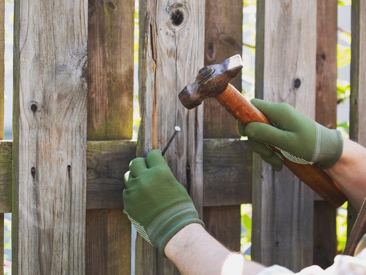 maintenance worker using hammer to fix fence