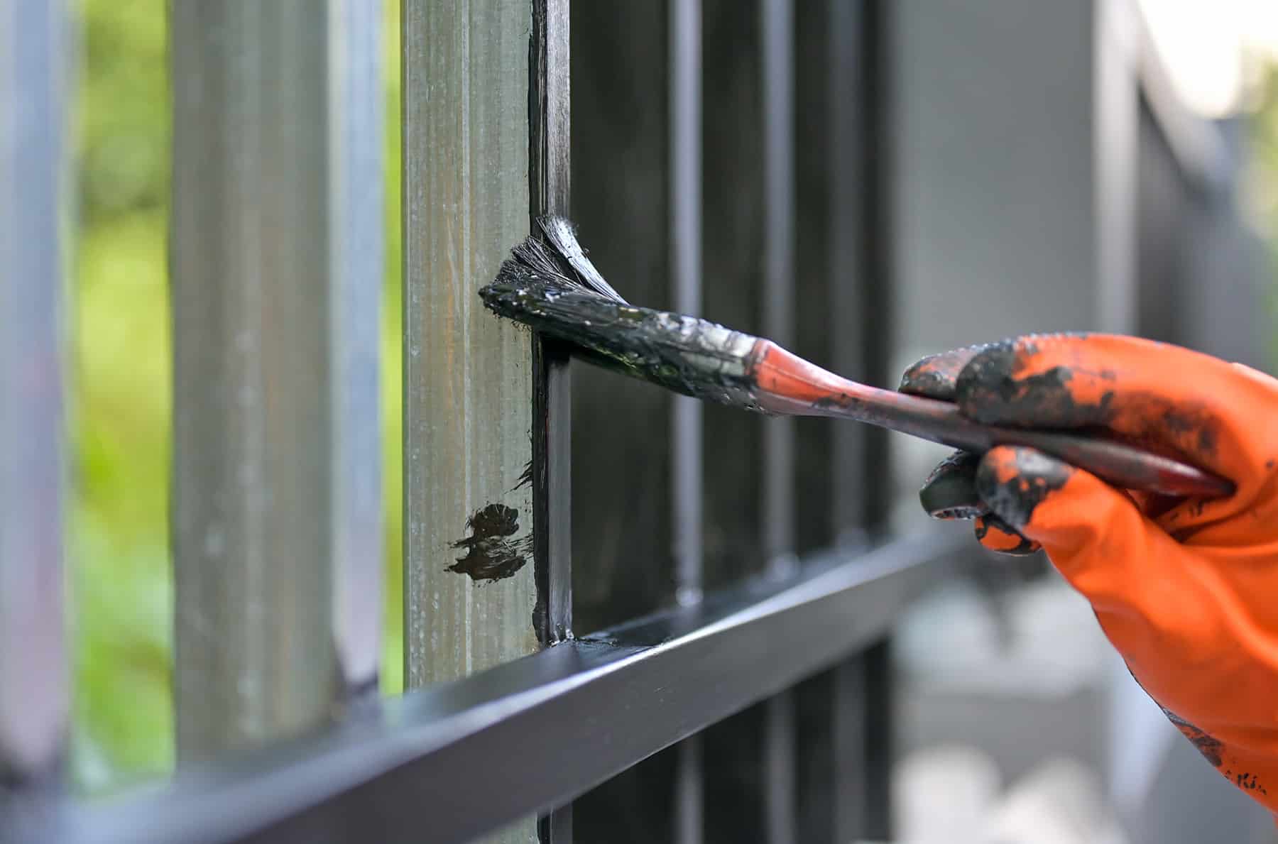 male painter painting fence