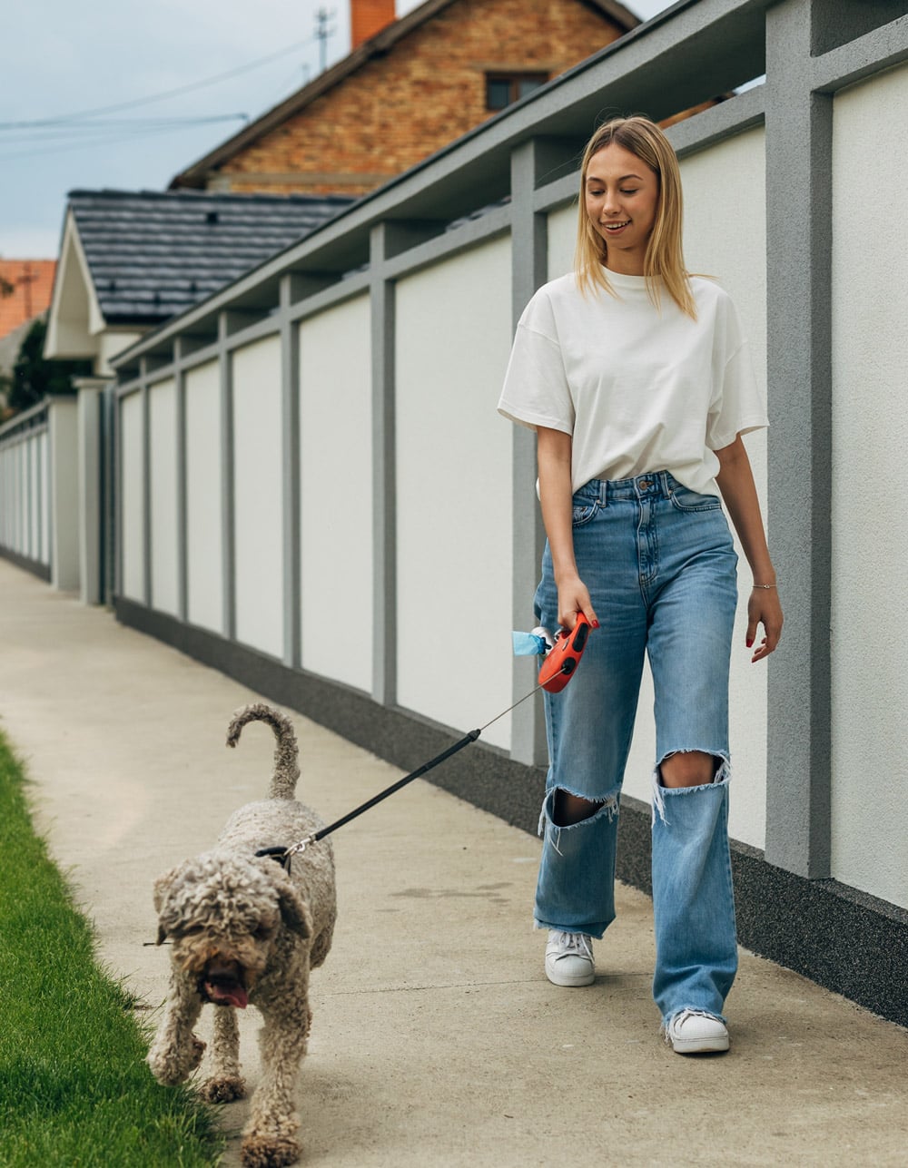 woman walking dog on sidewalk